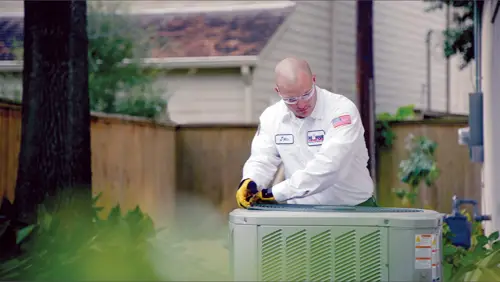 One Hour Air Conditioning & Heating technician carefully removing an AC handler outside a home in Birmingham, AL, ensuring expert HVAC service and efficiency.