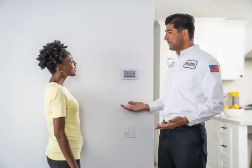 One Hour Air Conditioning & Heating technician explaining thermostat settings to a homeowner in Birmingham, AL.